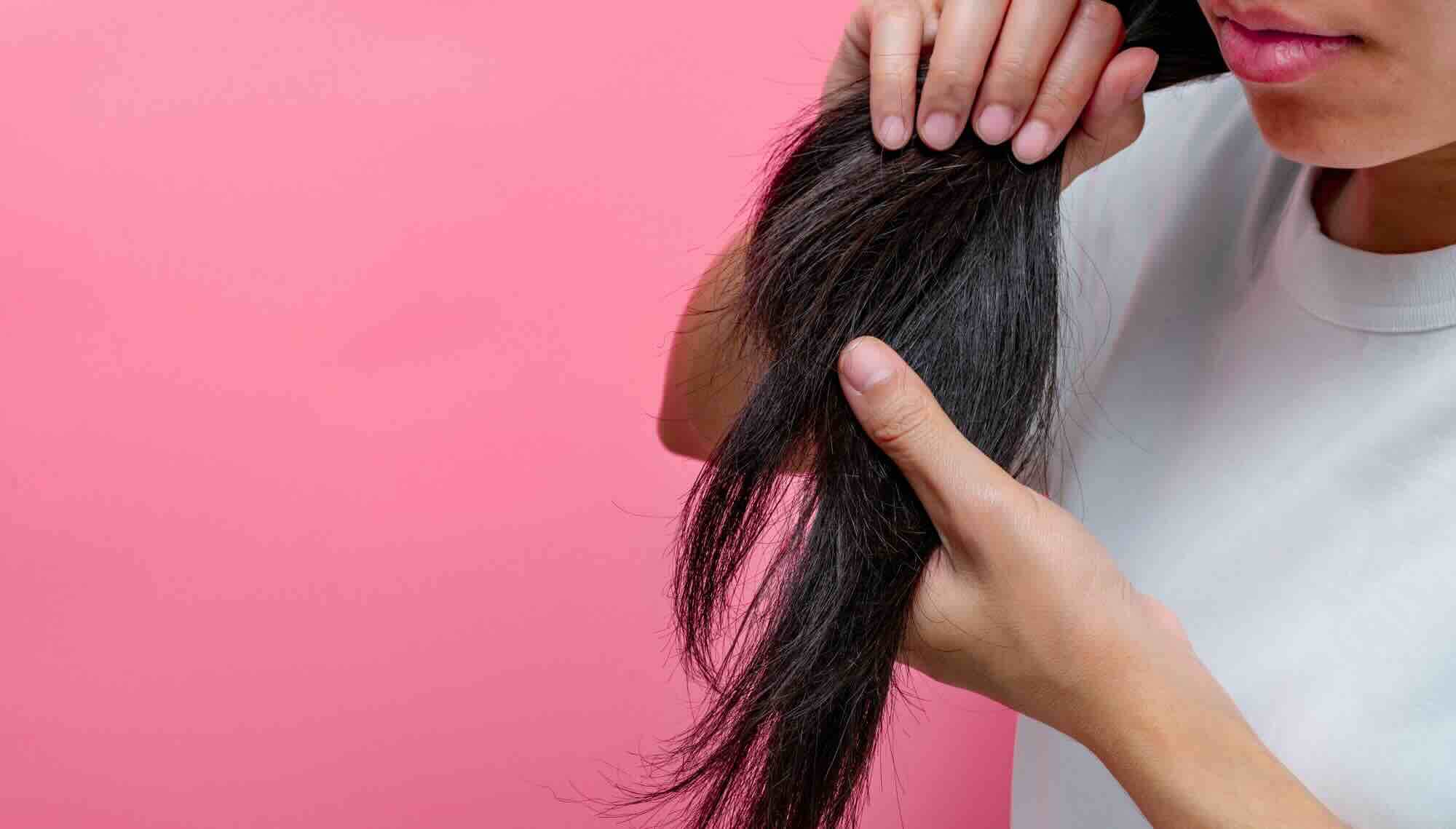 Vrouw houdt haar vast omdat ze kijkt naar haar dunne haar